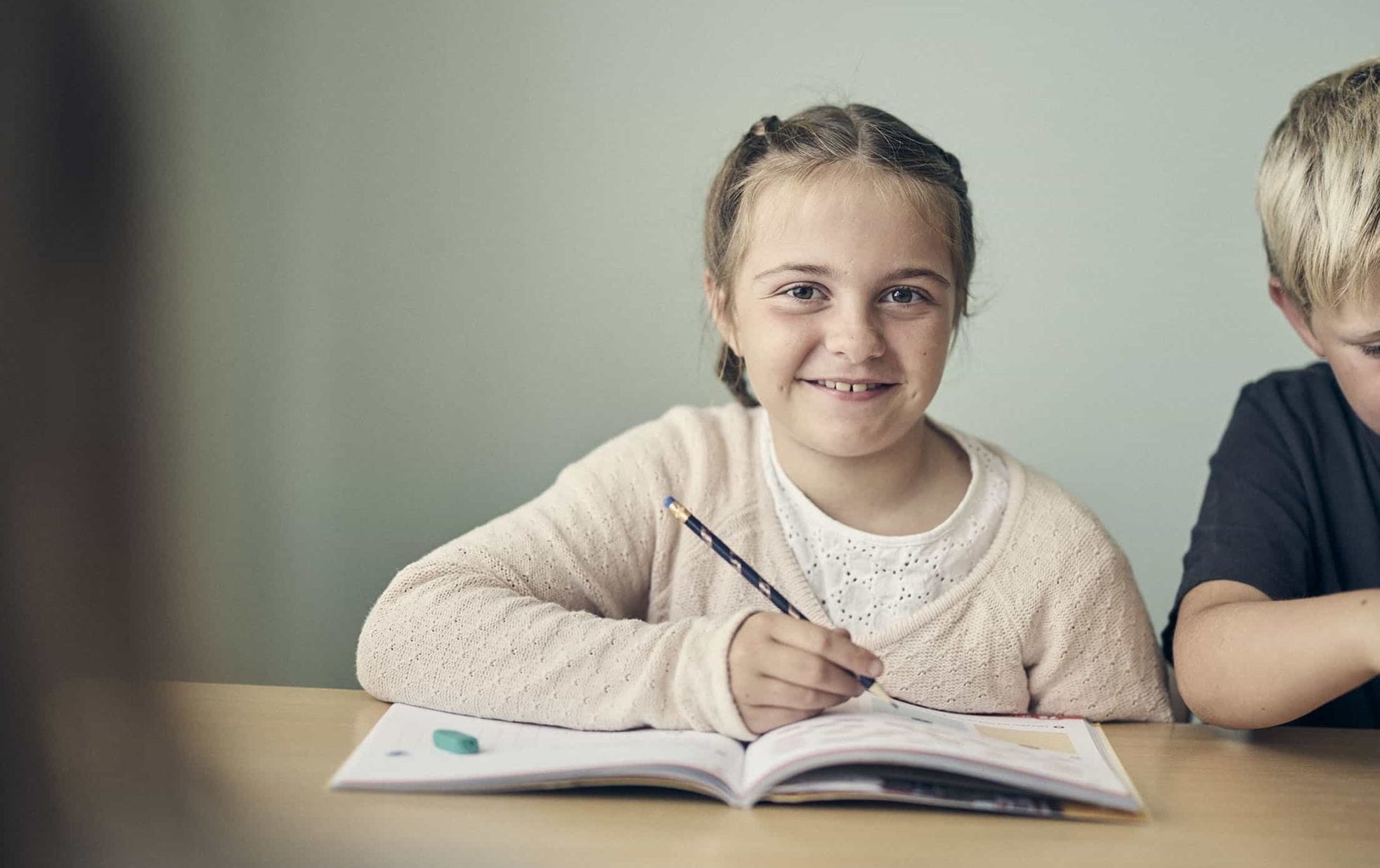 En glad elev på Noblaskolan skriver i en lärobok under en lektion.