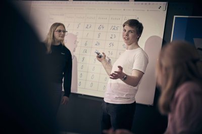 Två elever på Noblaskolan presenterar ett matematiskt problem på tavlan i ett klassrum.