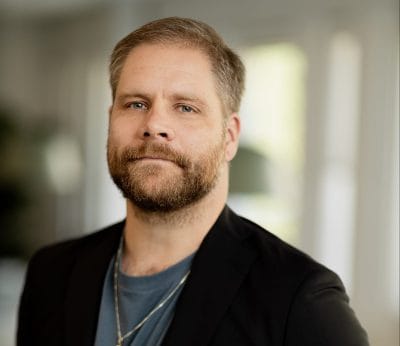 Rektor Erik i noblaskolans svarta kavaj med en nobla-logga på.