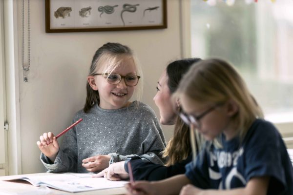 Tre elever på noblaskolan sitter i ett klassrum och gör skolarbete.