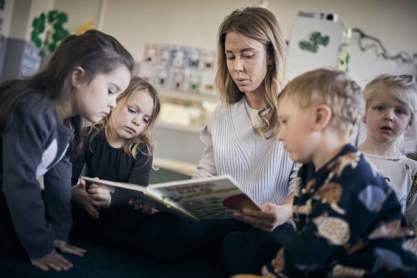 En pedagog sitter och läser för fyra elever.