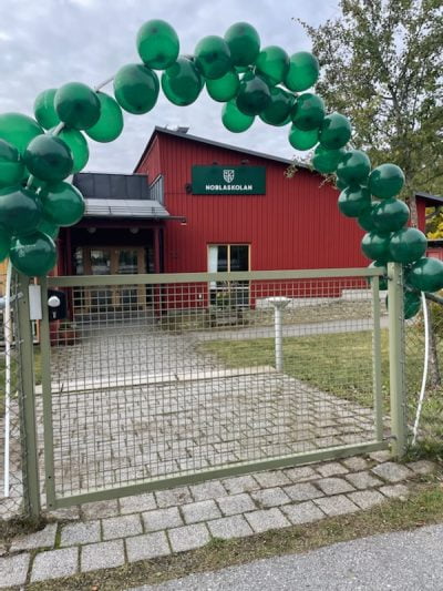 Noblaskolan Breviks fasad med ballonger på grinden.