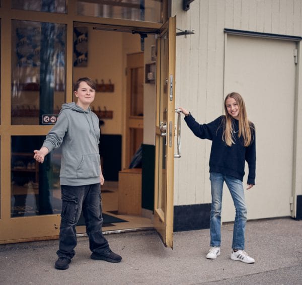 Två elever håller upp dörren till skolan.