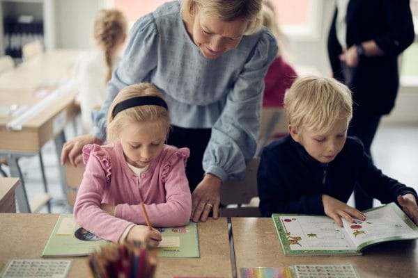 Lärare hjälper lågstadieelever i klassrum på Noblaskolan.