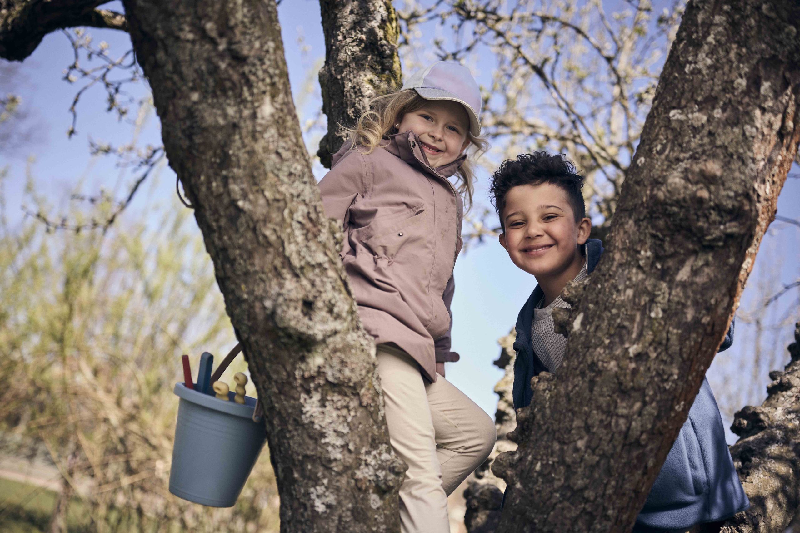Två glada elever som klättrar i ett träd.