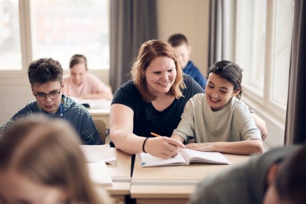 elev och lärare sitter vid bänken och skriver i boken.