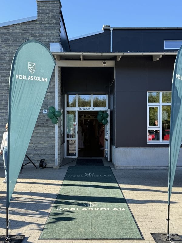 Löddeköpinges skolingång med en vippa bredvid dörren och en matta framför