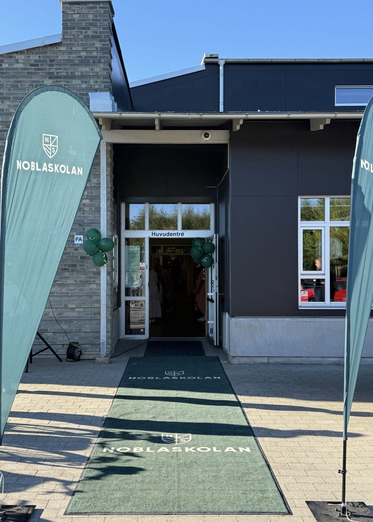 Löddeköpinges skolingång med en vippa bredvid dörren och en matta framför.