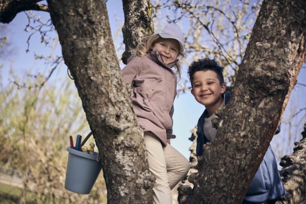 Två glada elever som klättrar i ett träd.