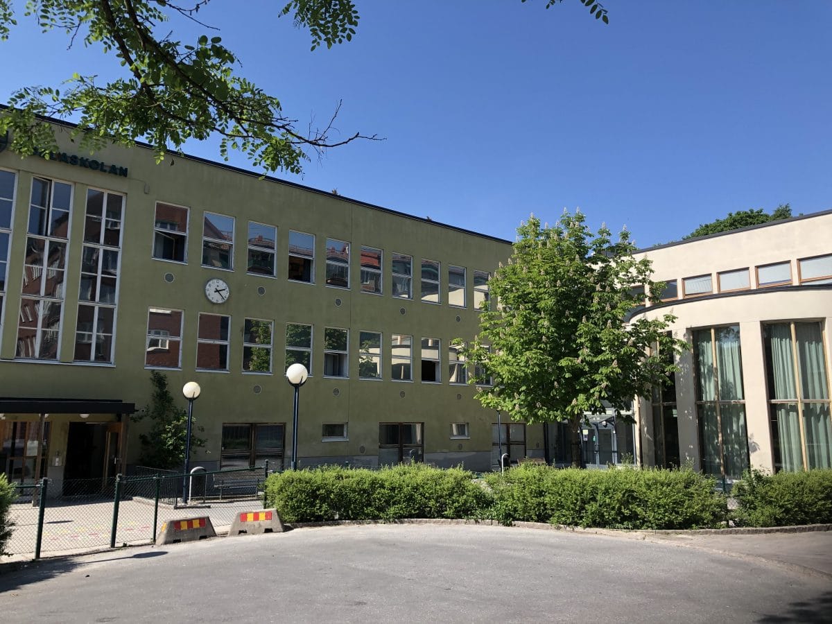 Noblaskolan Solnas skolbyggnad utifrån med skolgården.
