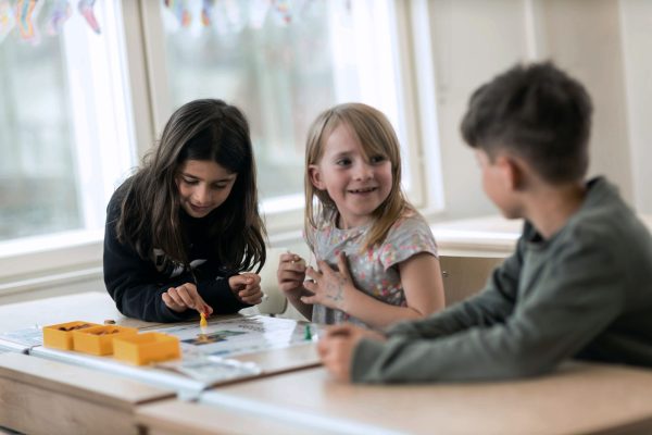 Tre elever i förskoleklass på Noblaskolan Täby sitter i ett klassrum.