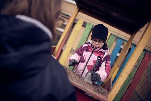 Förskolebarn på Noblaskolan leker med spade i utomhusmiljö.