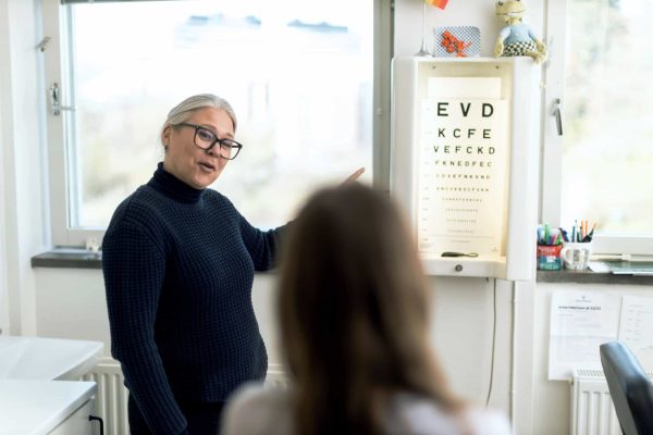 Skolsköterskan på Noblaskolan står vid en syntavla och undersöker en elevs syn.